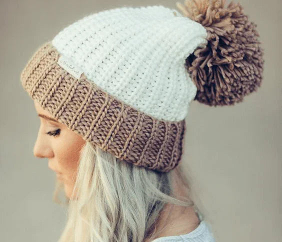Mujer de perfil con gorro tejido blanco y beige con pompón grande marrón