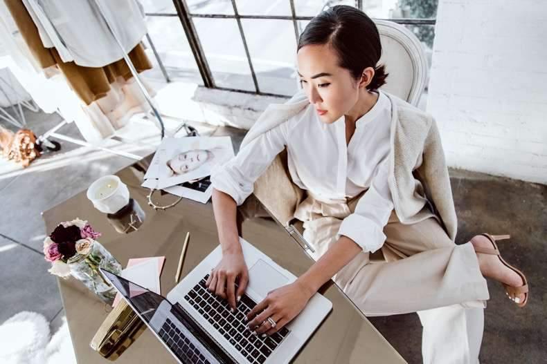 Mujer profesional en oficina moderna trabajando en laptop con estilo elegante y ambiente luminoso