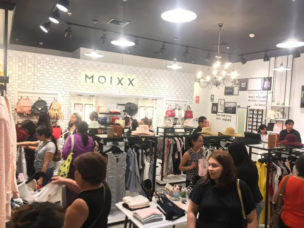 Tienda de ropa y accesorios Moixx con clientes comprando vestidos, bolsos y sombreros modernos