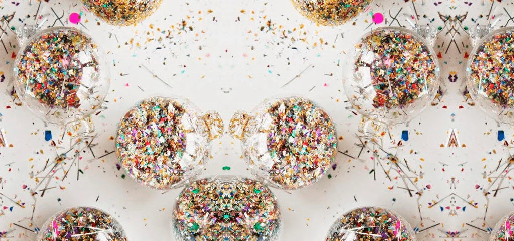 Esferas transparentes con purpurina multicolor sobre fondo blanco, decoración festiva brillante