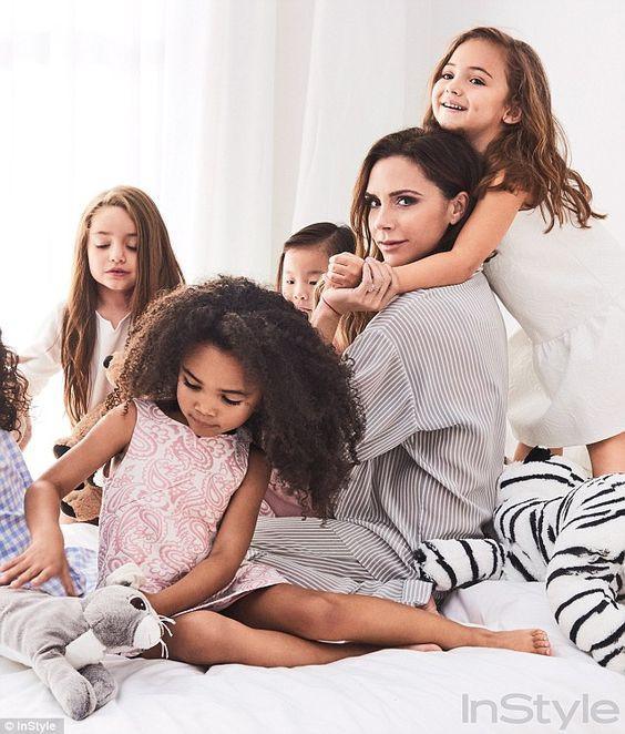 Mujer con cuatro niñas jugando en una cama blanca con peluches, ambiente familiar y alegre