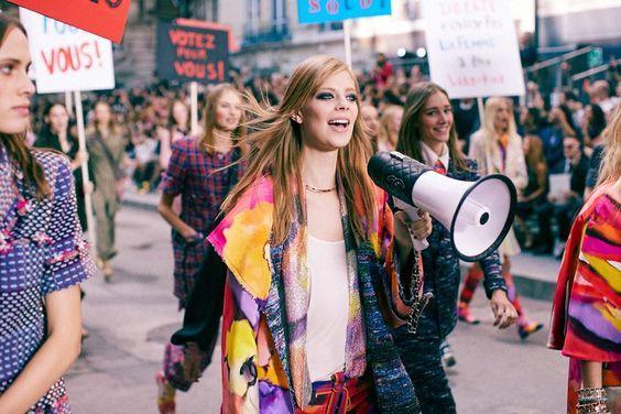 Mujeres jóvenes marchando con megáfono y carteles en desfile urbano con estilo de moda colorida