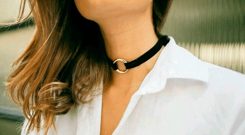 Mujer con blusa blanca y collar choker negro con aro dorado en el cuello