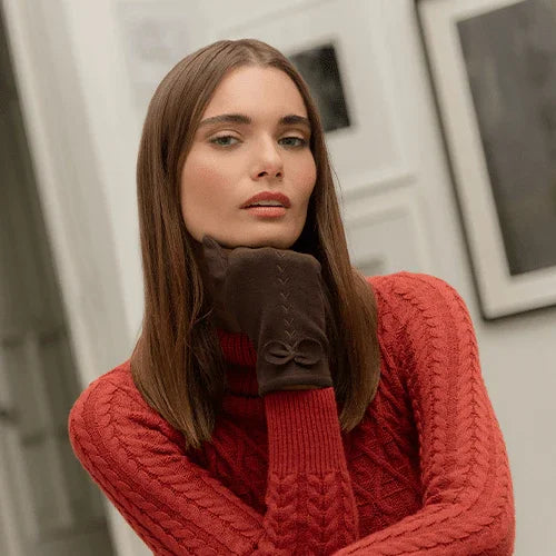 Mujer con suéter rojo de punto y guantes marrones en ambiente interior moderno