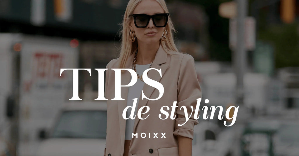 Mujer con gafas negras, blazer beige, y accesorios dorados en ciudad urbana, tips de styling