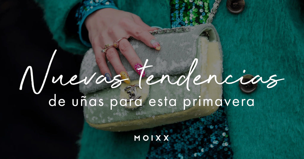 Mano con uñas pintadas de colores y bolso con lentejuelas en abrigo verde moda primavera
