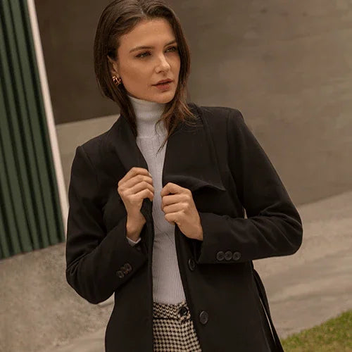 Mujer con abrigo negro y suéter blanco de cuello alto en exterior urbano, moda otoño invierno