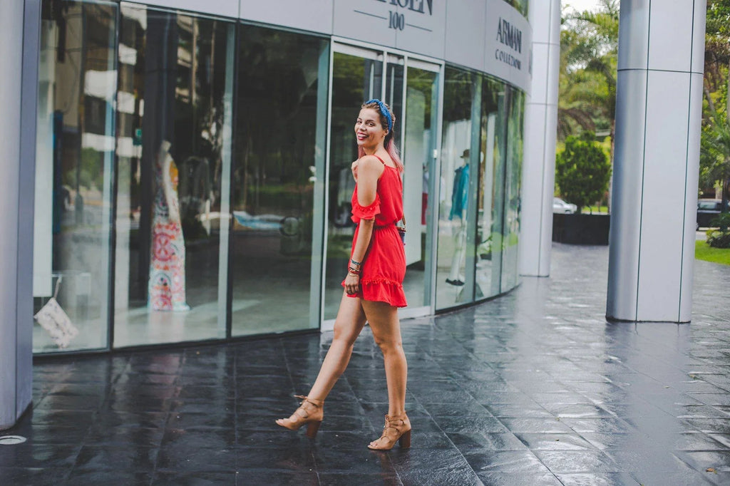 Mujer joven con vestido rojo y sandalias tacón caminando frente a tienda de ropa Armani en zona urbana
