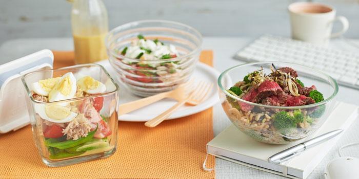 Almuerzos saludables para trabajo con ensaladas en recipientes de vidrio, huevos, atún y verduras frescas