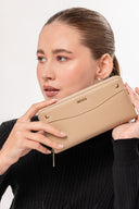Mujer con suéter negro sostiene cartera beige Moixx con cierre dorado en primer plano