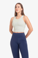 Mujer con top deportivo blanco y leggings azul marino en fondo blanco para ropa deportiva