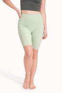 Mujer con short ciclista verde pastel y top gris oscuro, fondo blanco