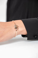 Pulsera dorada fina con colgantes y detalle de cristal en muñeca de mujer con camisa negra