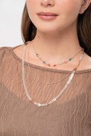 Collares dorados y coloridos sobre mujer con blusa marrón de encaje transparente
