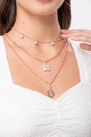 Collares dorados en capas con dijes de corazón y medalla sobre blusa blanca texturizada