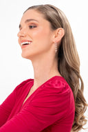 Mujer con vestido rojo y pendientes colgantes dorados con diseño de hojas, fondo blanco