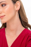 Mujer con arete colgante dorado con piedras y blusa roja, fondo blanco