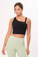 Mujer con top negro asimétrico y leggings verde claro en fondo blanco, ropa deportiva moderna