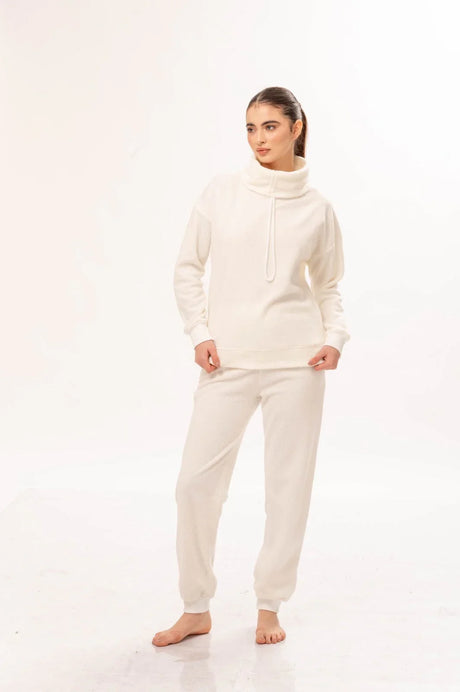 Mujer con ropa cómoda blanca de tela suave, sudadera de cuello alto y pantalones holgados