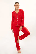 Mujer con pijama rojo de manga larga y pantalón largo con ribetes blancos en fondo blanco