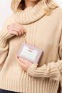 Persona con suéter beige sostiene billetera rosa claro con monedero plateado y llavero dorado MOIXX