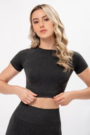 Mujer rubia con cabello rizado vistiendo conjunto deportivo negro de manga corta y leggings