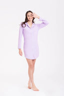 Mujer sonriente con camisón lila de manga larga y botones, fondo blanco minimalista